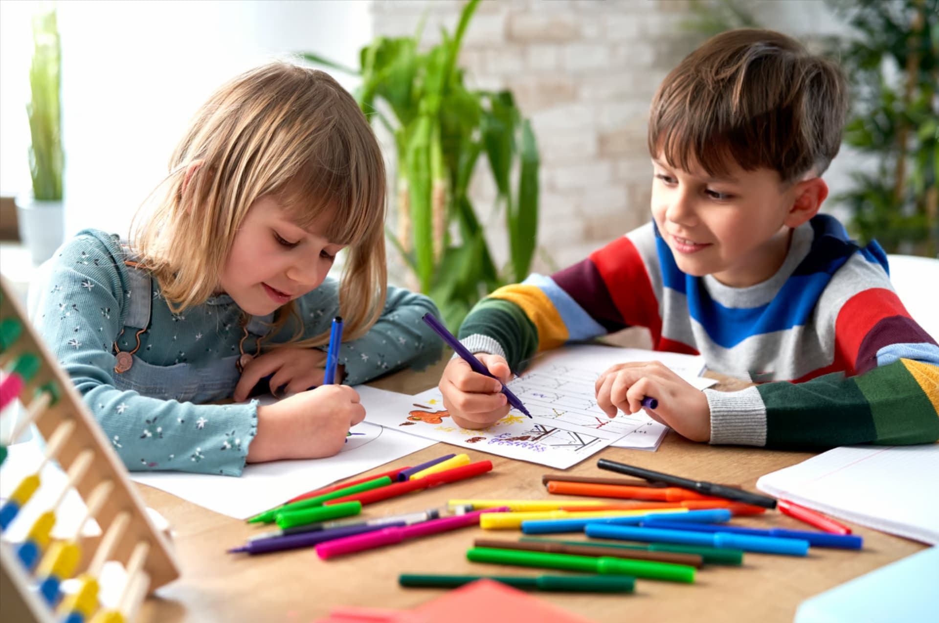 δύο παιδιά ζωγραφίζουν με μαρκαδόρους και μολύβια